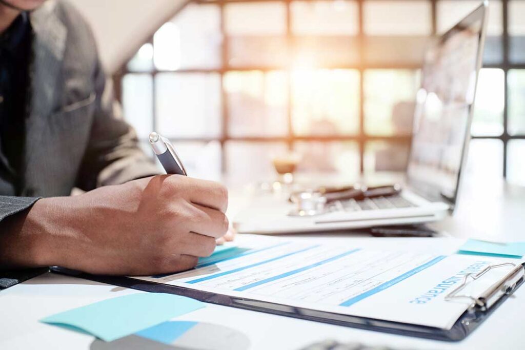 A couple reviews life insurance documents together at their kitchen table, with paperwork and a family photo nearby.