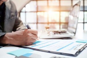 A couple reviews life insurance documents together at their kitchen table, with paperwork and a family photo nearby.